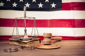 Law scales, judge gavel, handcuff, old book front USA flag